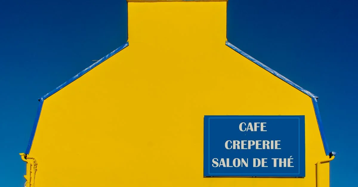 Façade de bâtiment jaune vif avec enseigne de café, de crêperie et de salon de thé.