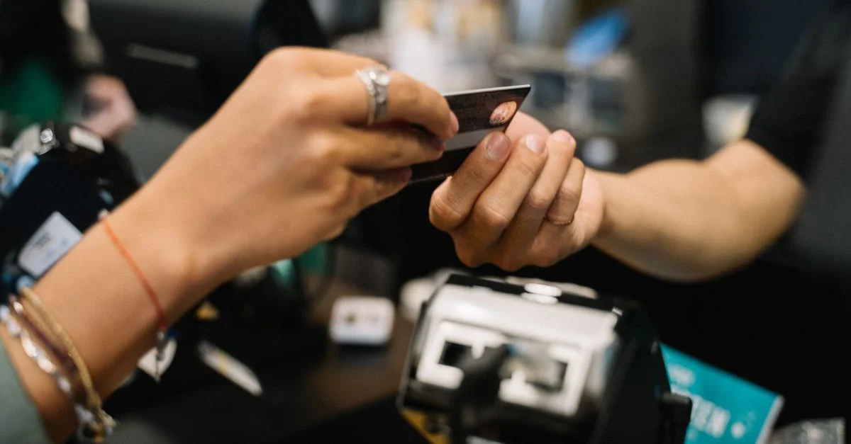 Gros plan sur des mains effectuant une transaction de paiement à la caisse d'un magasin avec une carte bancaire.
