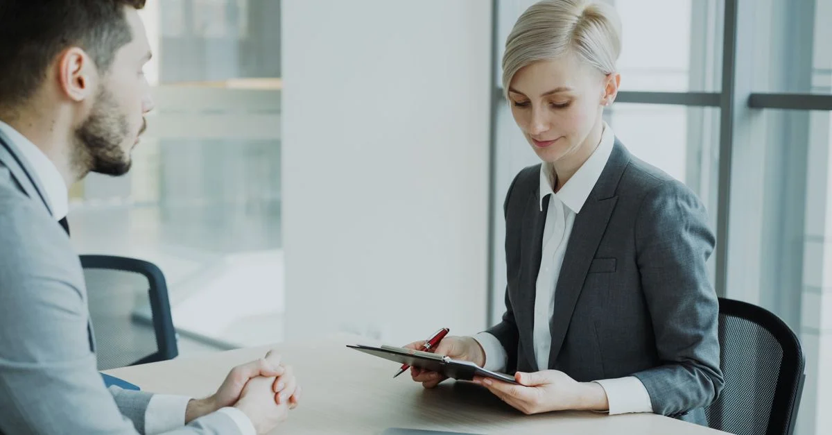 Deux professionnels dans un bureau moderne discutent affaires. Environnement lumineux et professionnel.