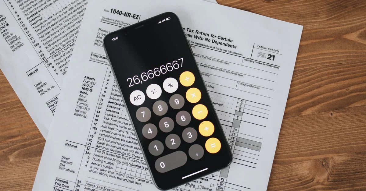 Vue de dessus d'une calculatrice smartphone sur des formulaires fiscaux pour les finances et la comptabilité.
